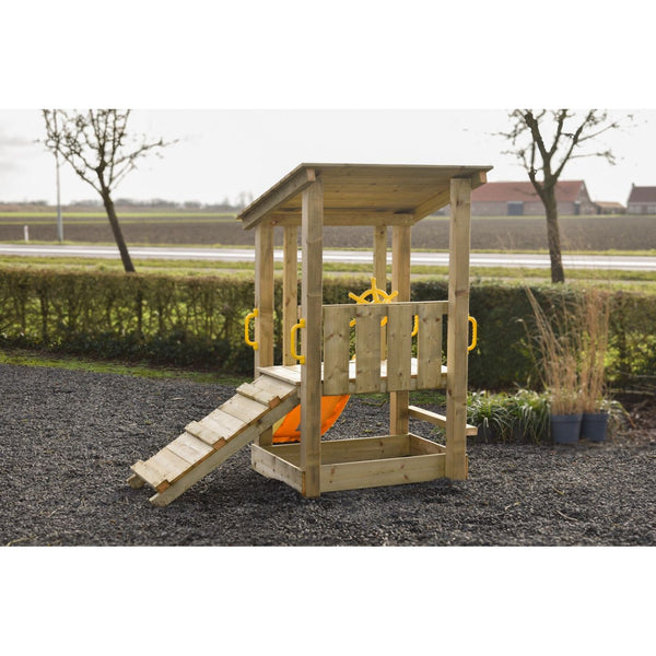 Holz-Spielturm für Kinder mit Dach, Leiter, Geländern, gelbem Steuerrad und orangefarbener Rutsche; steht auf Kies im Garten, Hintergrund Hecken, Bäume und Felder.